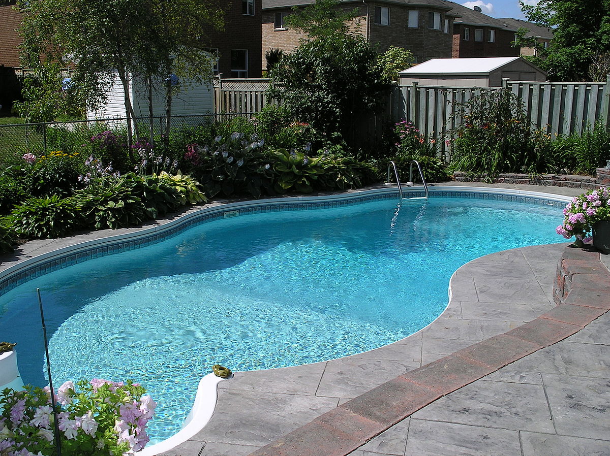 Stunning pool renovation in Brampton showcasing a sparkling blue pool with modern landscaping, lounge chairs, and outdoor lighting, ideal for summer gatherings and relaxation.