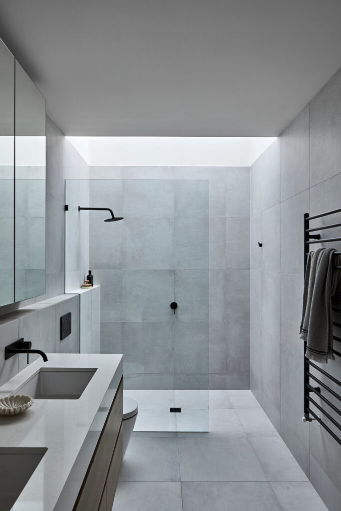 Modern bathroom showcasing a sleek shower with glass doors and a stylish sink with a contemporary faucet, featuring neutral tones and elegant fixtures.